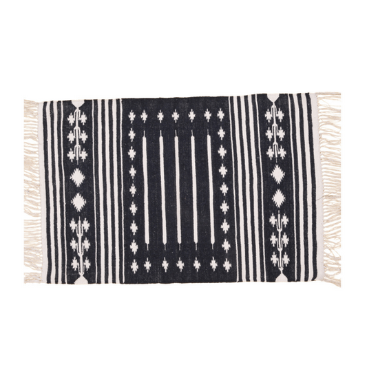 Introduce timeless elegance with this handwoven black and white traditional patterned cotton rug. Its intricate design exudes sophistication, while fringes add a charming accent. Durable and soft, it's perfect for enhancing your home decor with classic style and comfort.