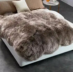 Luxurious Genuine Sheepskin Wool Area Rug draped over a modern bed, showcasing its plush texture and rich, natural tones. Perfect for enhancing comfort and style in your living room area rugs collection.