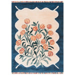 The Blossom Haven Sanctuary Hand Tufted Wool Rug features a vibrant floral design with orange blossoms and green leaves against a creamy beige background. The rug is bordered by a rich blue frame, adding a touch of elegance to any room. This area rug combines traditional craftsmanship with modern aesthetics.