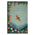 The Cloudsong Flight Hand Tufted Wool Area Rug features an artistic design of a vibrant bird soaring over stylized mountains and surrounded by colorful flowers. This elegant wool rug brings a touch of nature and tranquility to any room.