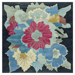 A vibrant Organic Flame Garden Hand Tufted Rug featuring a bold floral design with red, blue, and yellow flowers on a dark background. This square area rug is a perfect contemporary addition to living rooms, crafted from high-quality wool for durability and comfort.