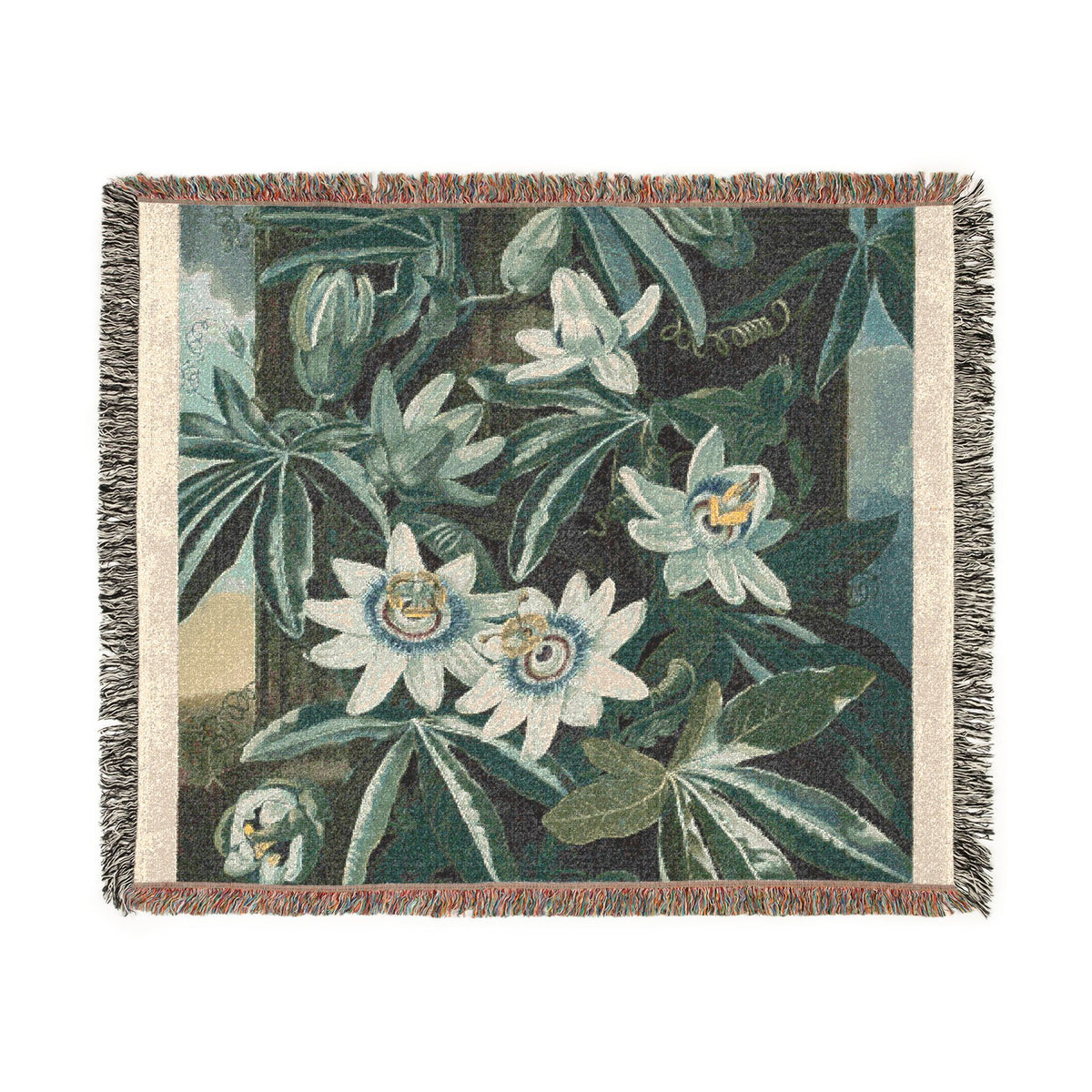 A square woven throw blanket featuring a botanical tapestry design with white passion flowers and green leaves on a dark teal background, finished with beige borders and fringed edges.