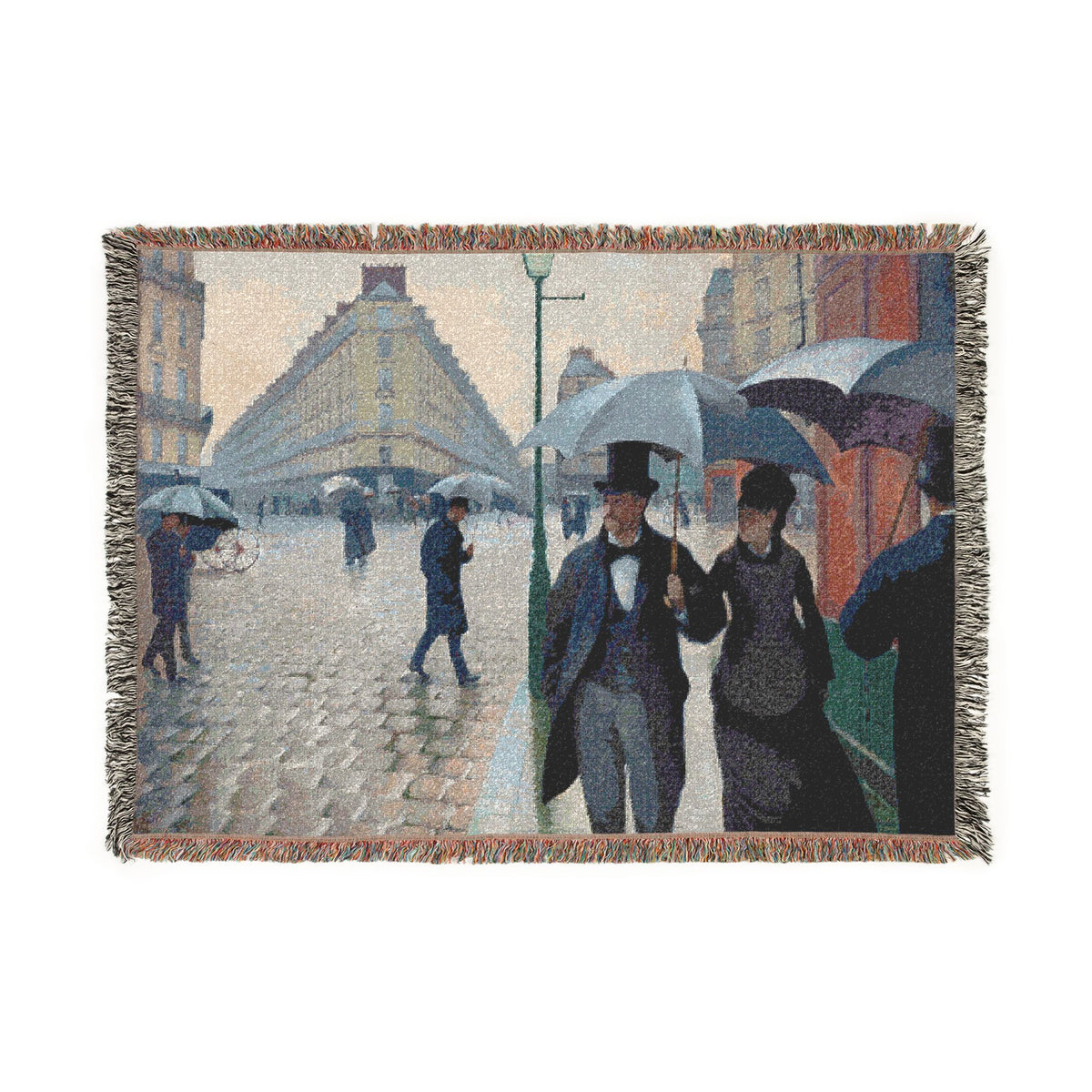 A woven throw blanket featuring a pointillist painting of a Parisian street scene with pedestrians holding umbrellas, finished with fringed edges, shown against a plain white background.