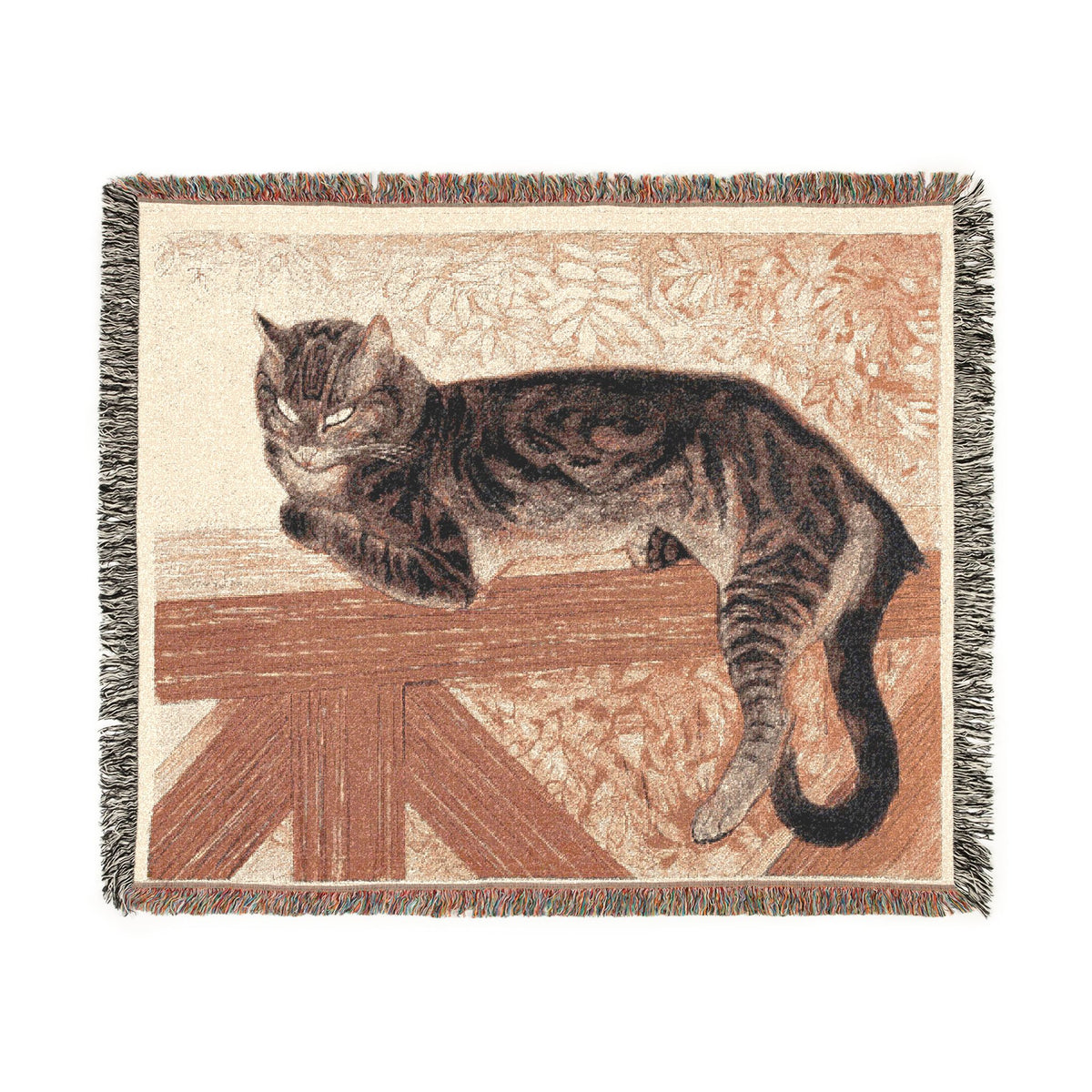 A woven throw blanket featuring a tabby cat lying on a wooden fence, with a cream background and multicolor fringe along the edges.