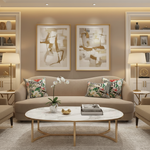 A modern living room featuring a beige sofa with two patterned accent pillows, two framed abstract wall art prints, a round white marble coffee table with gold legs, and built-in shelving with lit lamps on either side.