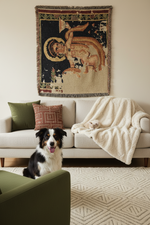 A woven wall tapestry featuring a classical figure with a halo, displayed above a beige sofa in a living room setting with a dog and a cat.