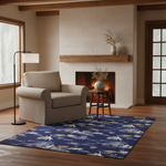 A navy blue area rug with a white and beige Japanese wave and crane pattern, styled in a cozy living room with a beige armchair, a lit fireplace, and a black floor lamp.