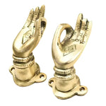 Two brass hand-shaped cabinet pulls with engraved palms in a mudra gesture