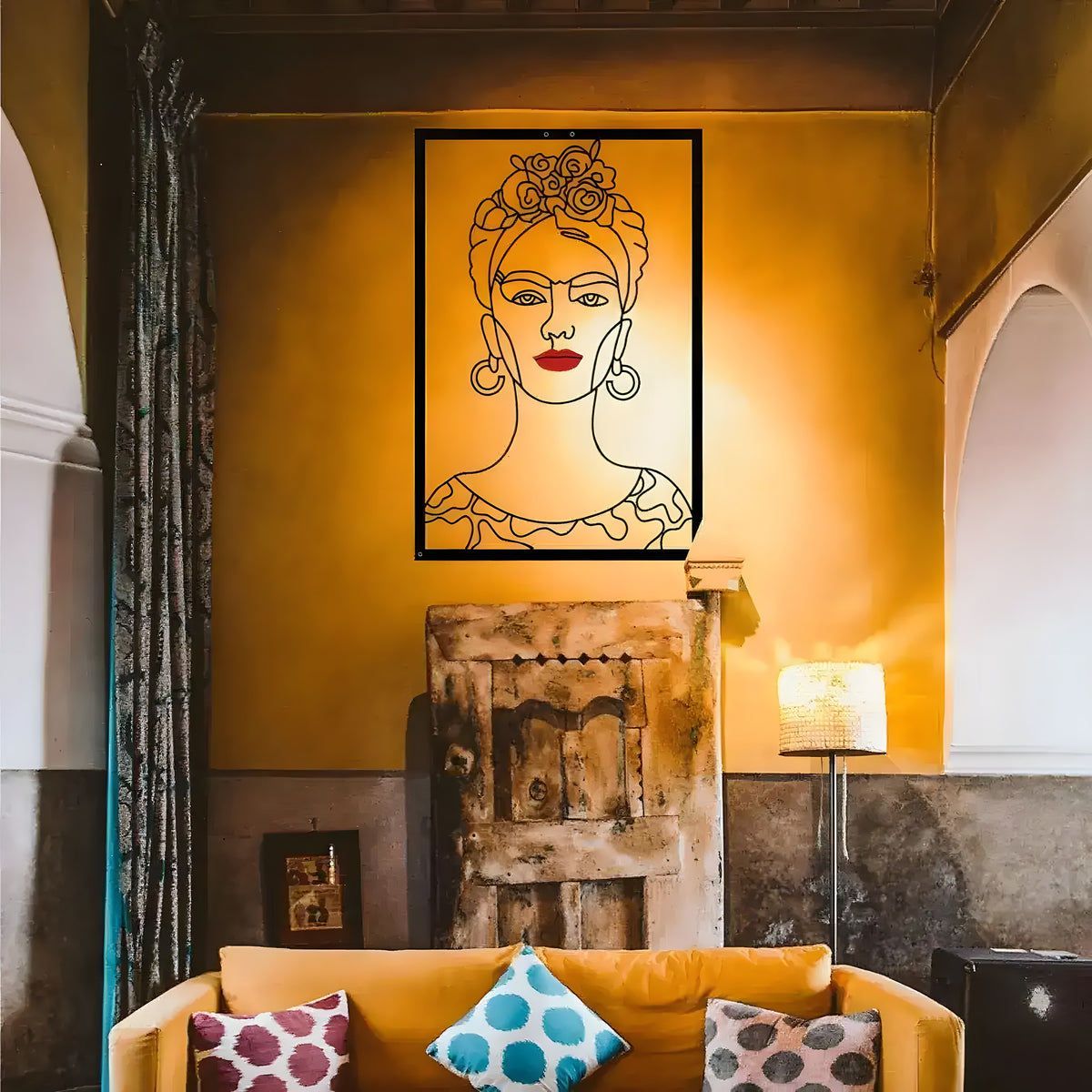 Black single-line Frida Kahlo portrait metal art with floral crown and red lips, on a gold wall