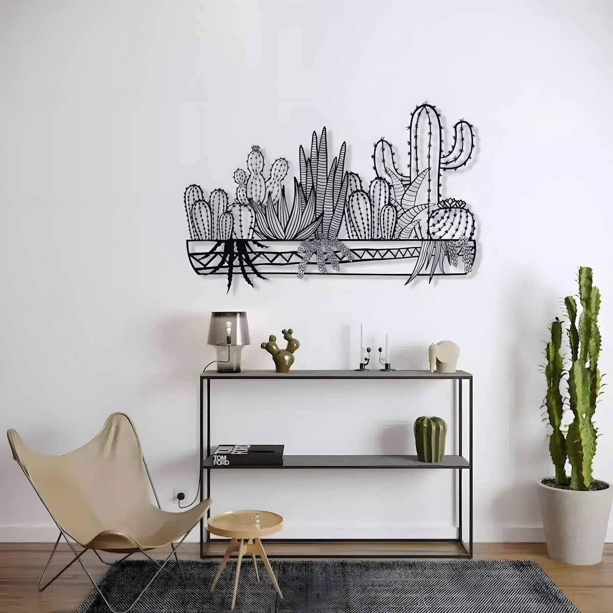 Black metal cactus wall decor art of assorted cacti in a trough above a console table
