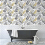 Gold contrast black palm leaves wallpaper in a bathroom above white subway tile and a gray clawfoot tub