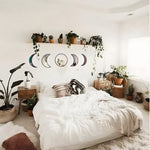 5 moon phase accent wall mirrors arranged horizontally above a boho bed surrounded by potted plants