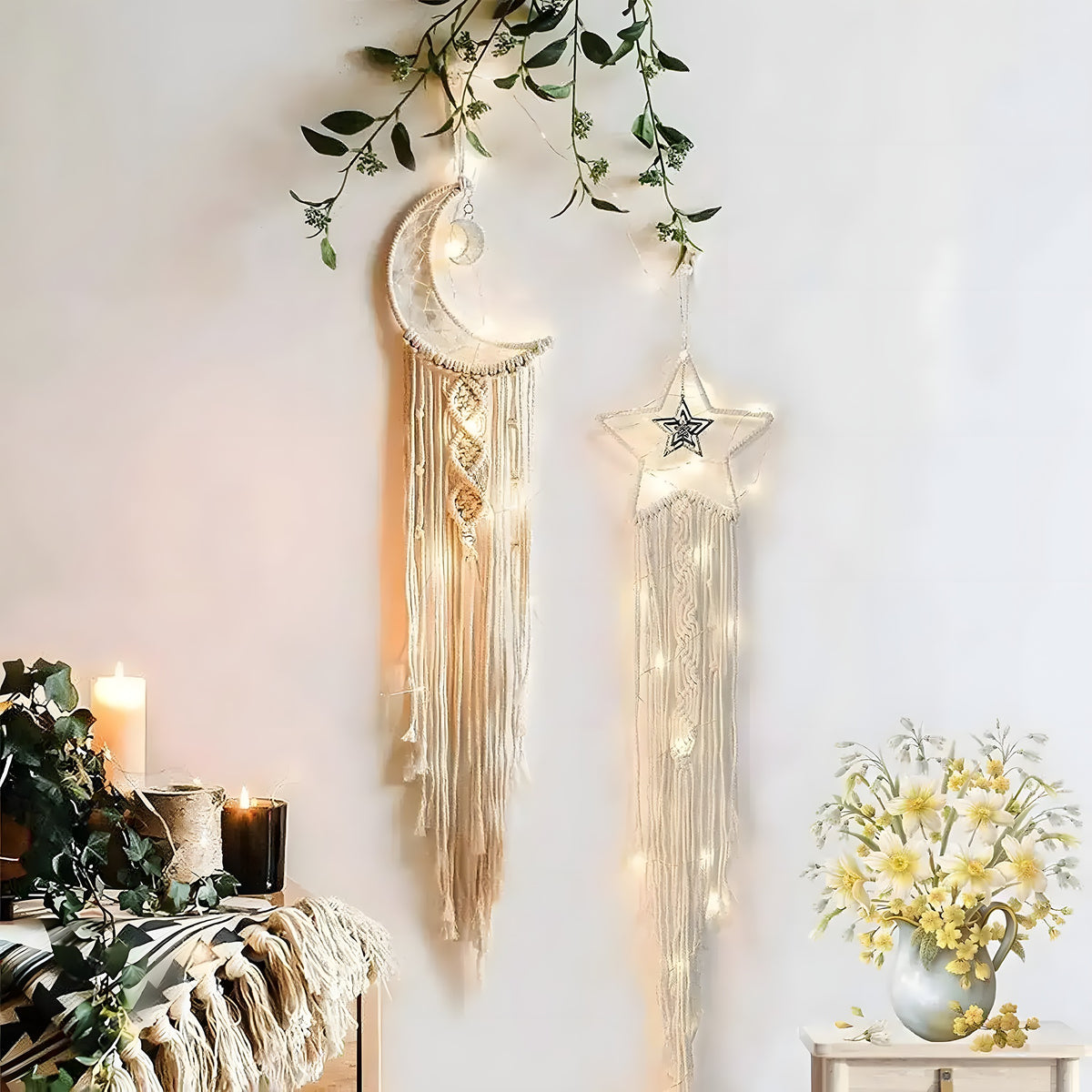 Moon and star macramé dream catchers with long fringe on a white wall draped with greenery