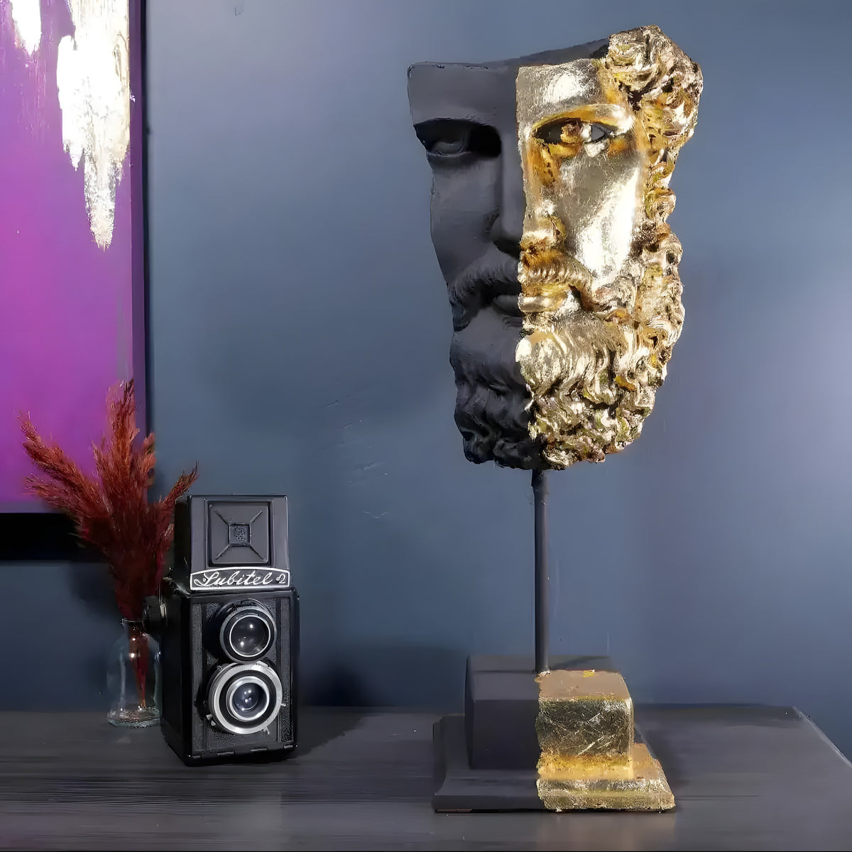 Zeus bust sculpture on stand, face split between matte black and gold leaf