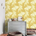 Yellow and white floral wallpaper with cascading white blossoms, behind a grey dresser with baskets