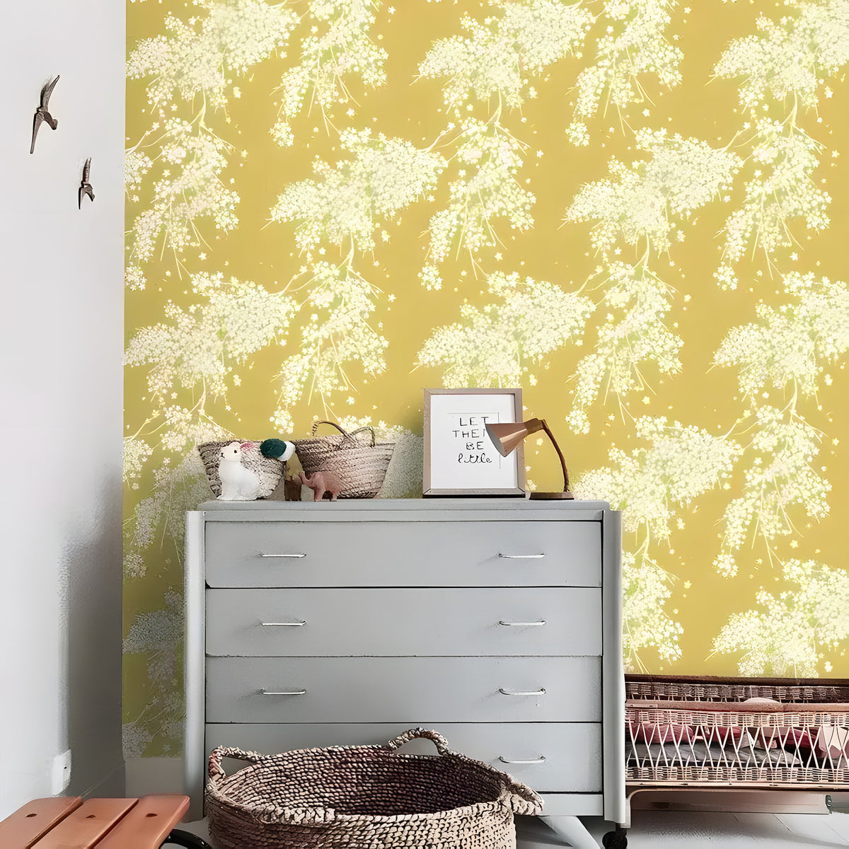 Yellow and white floral wallpaper with cascading white blossoms, behind a grey dresser with baskets