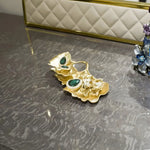 Gold gingko-leaf trinket dish with emerald and clear crystal accents on grey marble