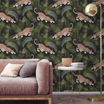 Dark jungle wallpaper with prowling jaguars among green palm leaves behind a pink sofa