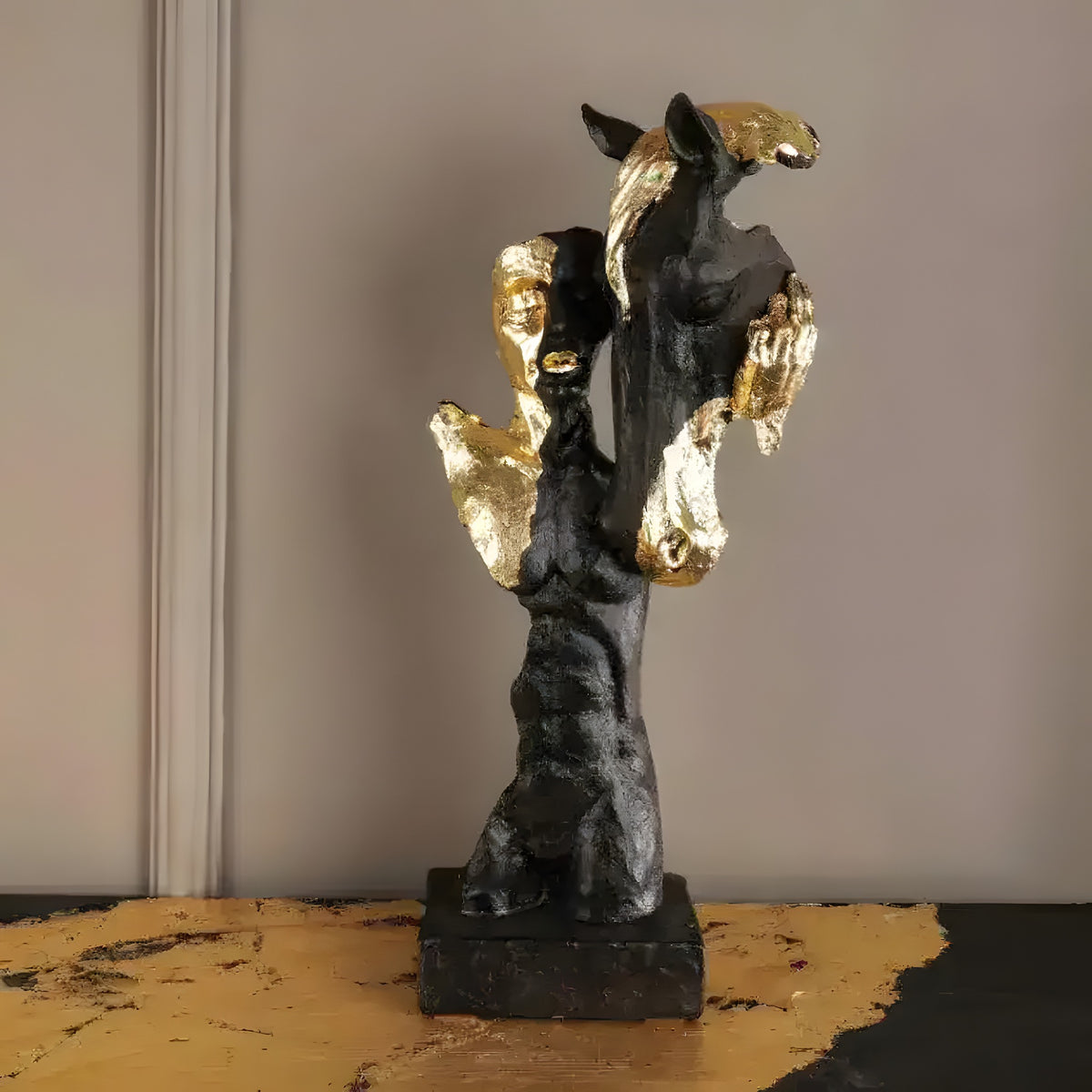 Abstract black man and horse statue with gold gilded accents on a square base