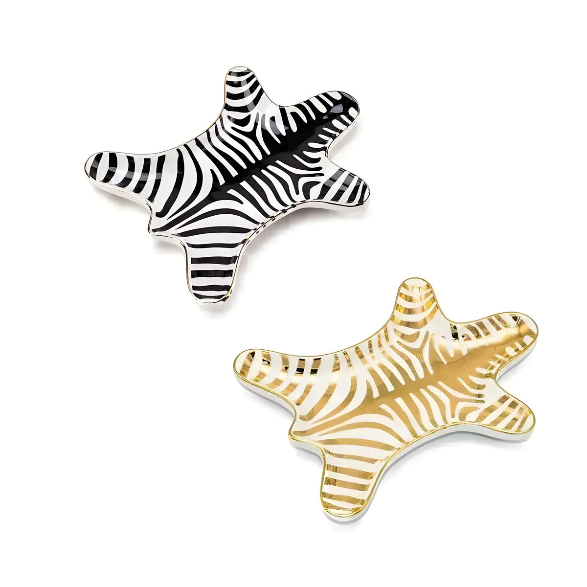 Two zebra-hide-shaped ceramic trinket dishes, one black-striped, one gold, on white