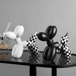 White, black and checkered balloon dog figurines grouped on a black glass table