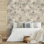 Neutral beige geometric wallpaper with concentric circles behind a white bed with throw pillows