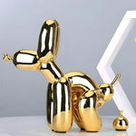 Glossy gold balloon dog figurine in squatting pose with a small gold poop pile, on marble