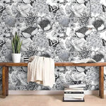 Black-and-white butterfly and floral wallpaper behind a wood bench with a knit throw