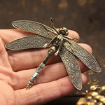 Detailed brass copper dragonfly figurine with textured filigree wings, held in a hand