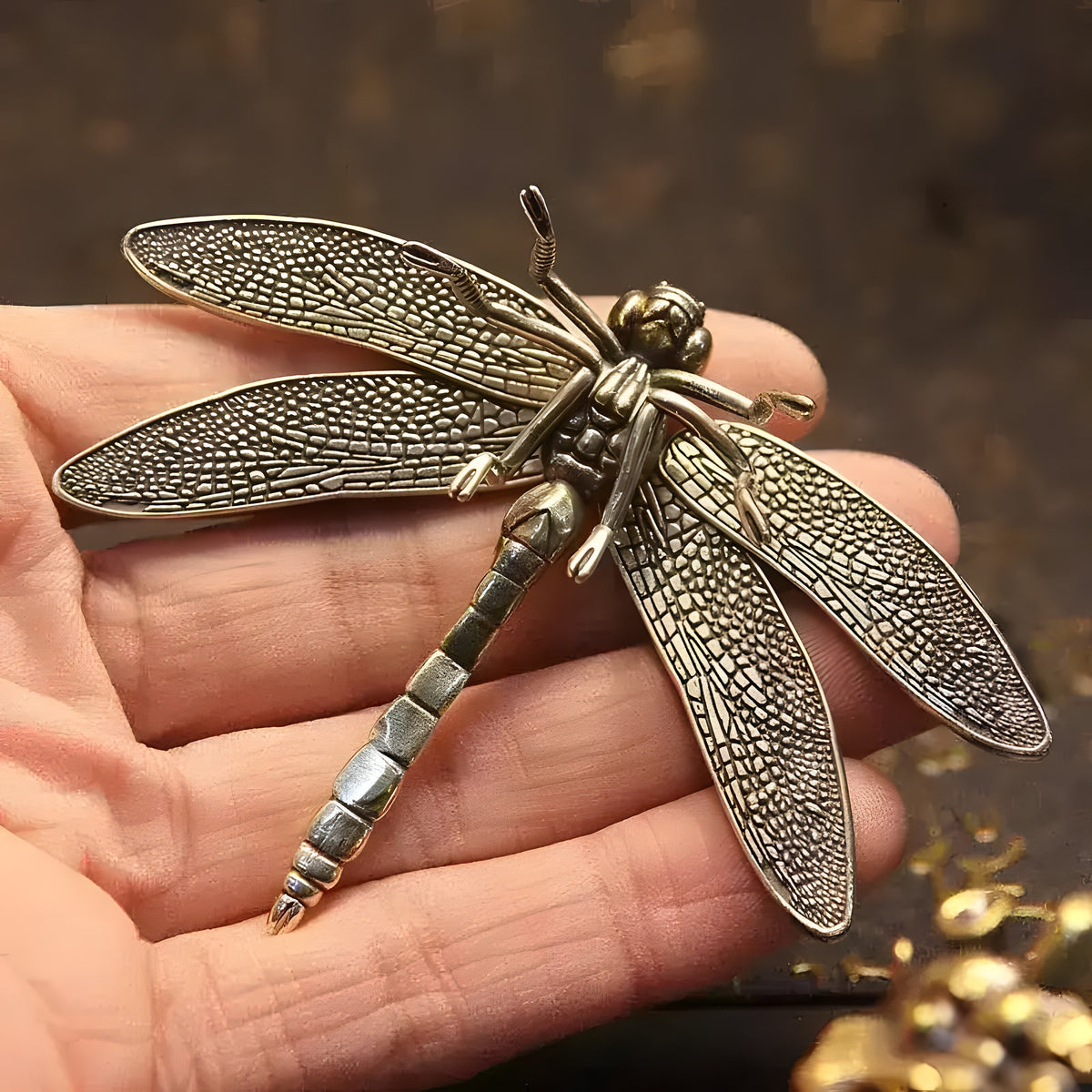 Detailed brass copper dragonfly figurine with textured filigree wings, held in a hand