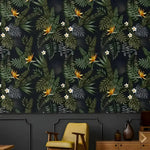 Dark navy tropical leaves and flowers wallpaper with orange bird-of-paradise blooms, yellow chair setting