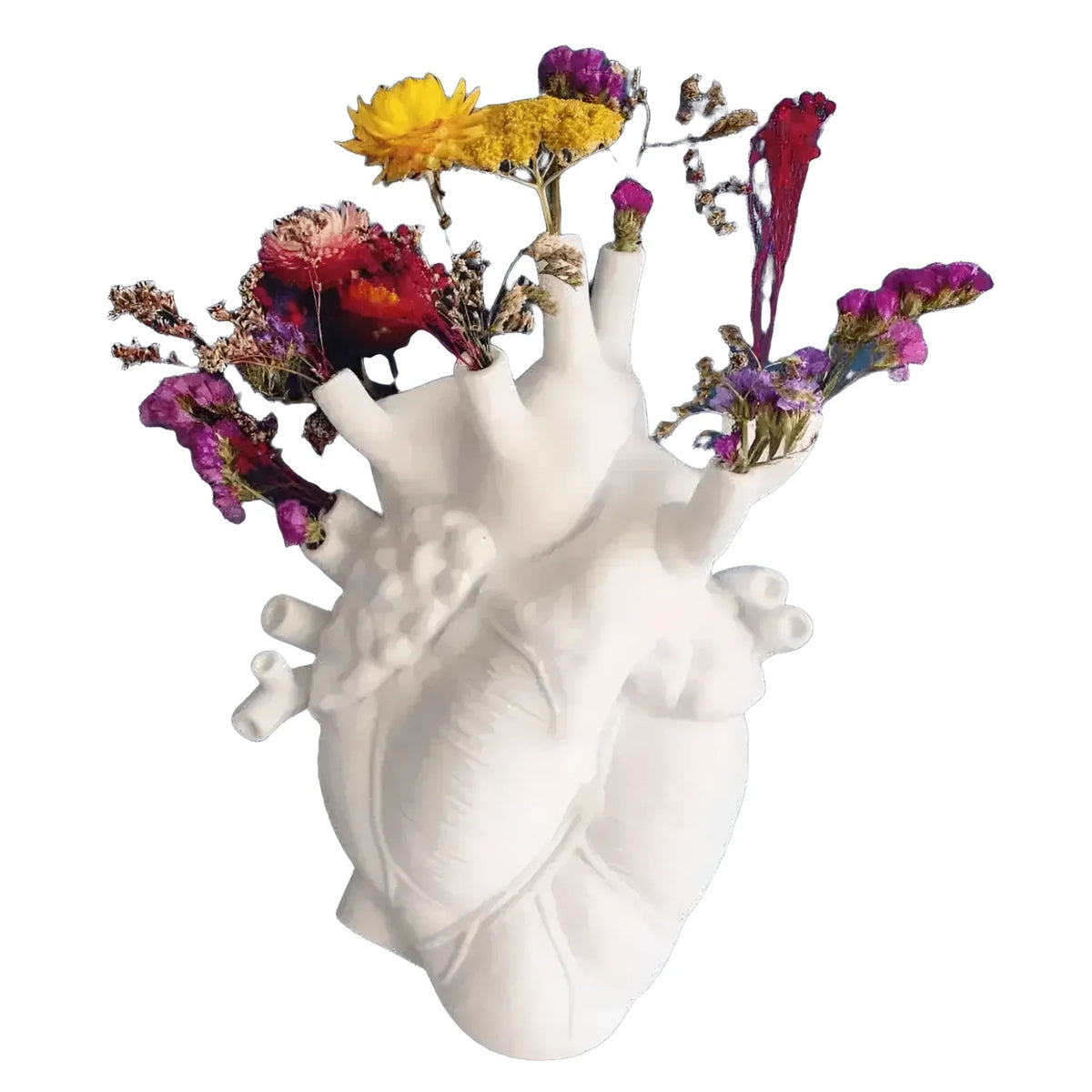 White ceramic anatomical heart vase with colorful dried flowers — purple, yellow, red — emerging from openings