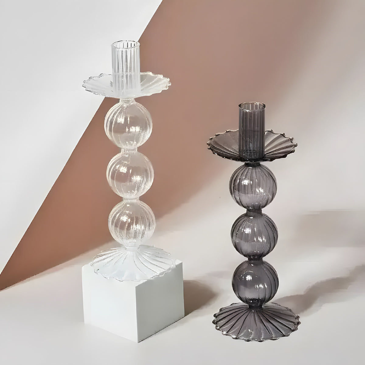 Clear and dark grey Viki glass candle holders with ribbed bubble-stacked towers and scalloped drip trays, two-tone background