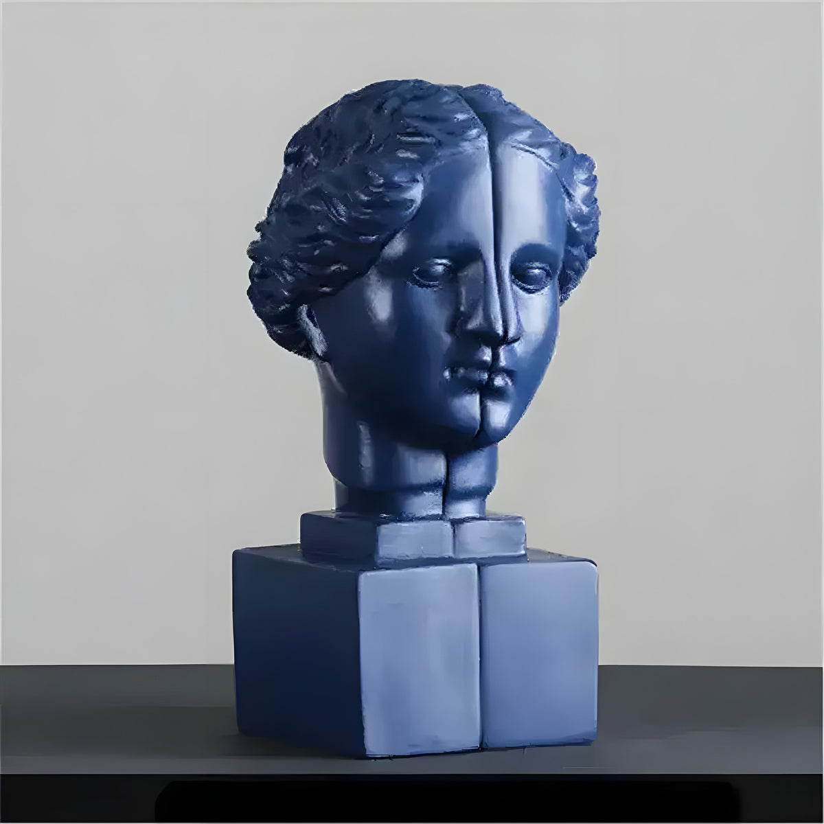 Navy blue resin split goddess head bookend on square pedestal, grey studio background