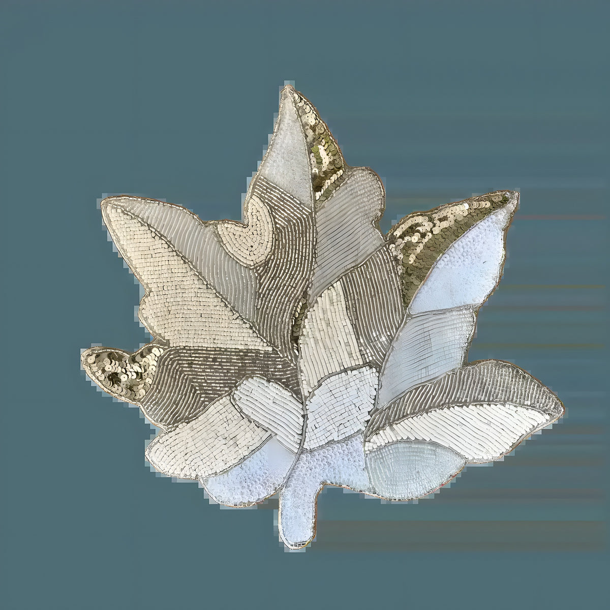 Off-White Beaded Maple Leaf Placemat maple leaf shape with intricate silver and gold seed bead embroidery on light background