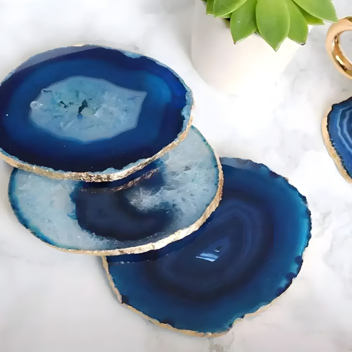 Blue agate coasters with concentric navy and sky-blue rings and gold edges stacked on a white marble surface