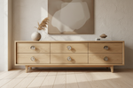 A light natural wood six-drawer sideboard or credenza with round metal knobs, styled in a minimalist room with a textured beige wall, a framed abstract print, and a vase with dried grass.