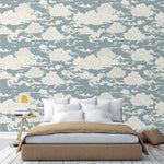 Bedroom with chinoiserie clouds wallpaper in dusty blue with swirling white cloud motifs, bed and nightstand in front