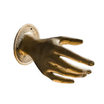 Polished brass hand-shaped door pull with open fingers on round textured backplate, white background