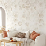 Beige watercolor honeycomb wallpaper in boho living room behind white sofa with terracotta cushions and arch