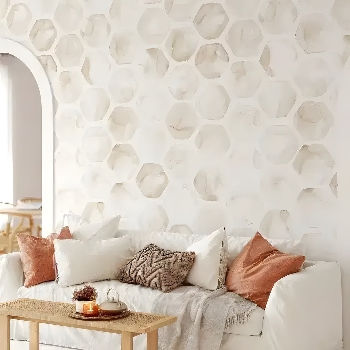 Beige watercolor honeycomb wallpaper in boho living room behind white sofa with terracotta cushions and arch