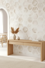A light natural wood console table in a bright, modern room with a white honeycomb-patterned wall, a beige rug, and decorative dried grass in a vase.