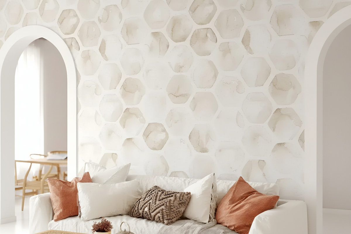A styled living room scene featuring a white sofa with white and rust-colored pillows, set against a prominent white honeycomb-patterned accent wall with arched openings on either side.