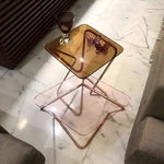 Square Crystal Table with transparent crystal side table top and brass base, on herringbone floor beside a couch