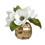 White artificial magnolia blooms with green leaves in small faceted gold pot, gray background