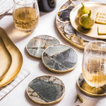 Four round green aventurine agate coasters with gold trim styled on white table with wine glasses and figs