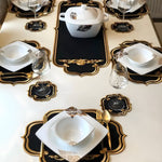 Black and gold embroidered royale table linen 13-piece set laid on a dining table with dishes and wine glasses