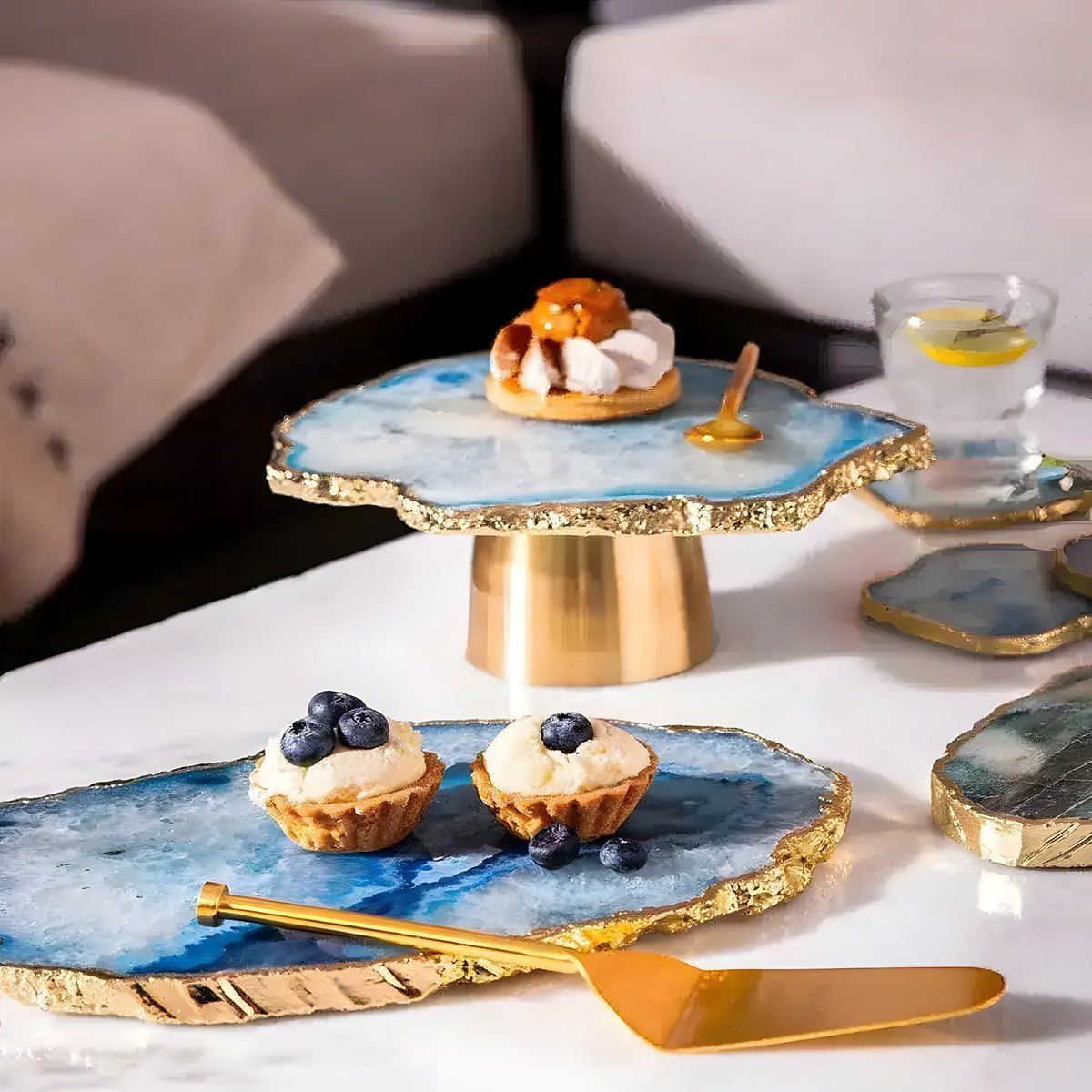 Blue agate cake stand with gold base styled on table with mini tarts, gold server, agate coasters and glass, lifestyle