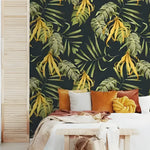 Yellow-green tropical wallpaper on bedroom accent wall — dark navy with monstera and palm leaves, white bed below