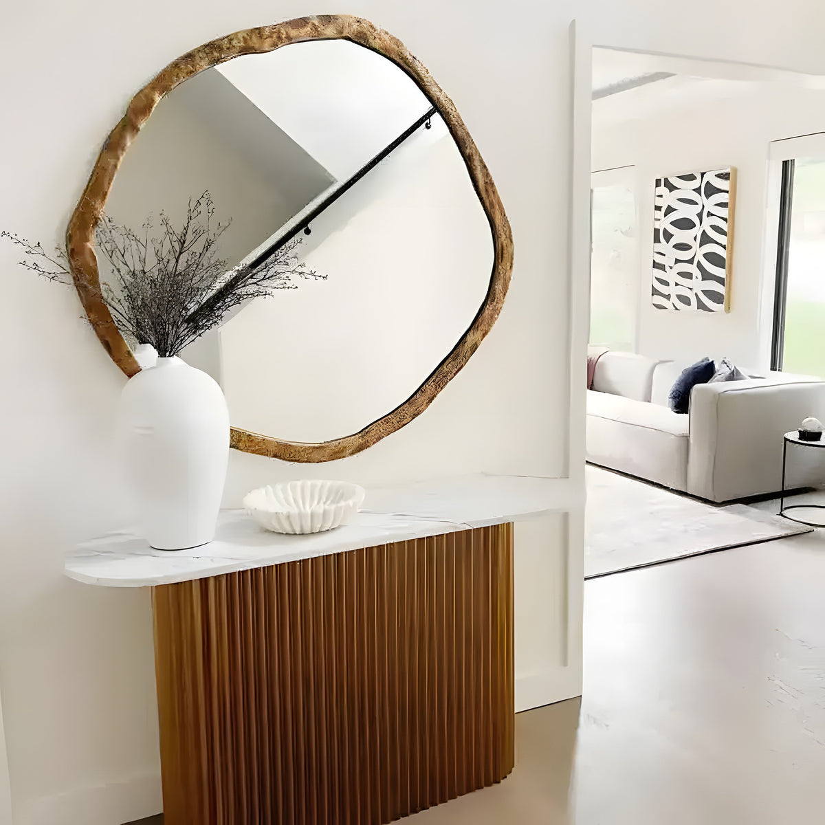 Wavy marble fruit bowl on marble console table beneath organic-edge mirror in modern entryway
